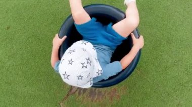 4k video of little boy sitting on carousel on playground and rotating fast