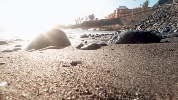 Närbild 4k video av lugn sandstrand med stora stenar och klippor i solnedgången ljusstrålar — Stockvideo