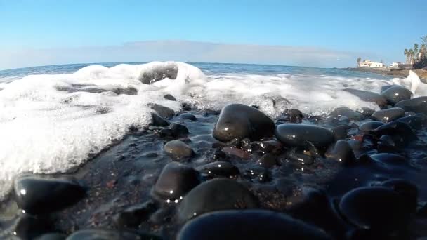 Primer plano video en cámara lenta de la ola oceánica rodando en la playa con guijarros negros — Vídeos de Stock