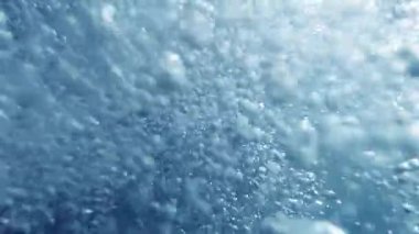 Sualtı dalgıcının okyanusun dibinden hava kabarcıkları salıp nefes alışını gösteren yavaş çekim videosu.