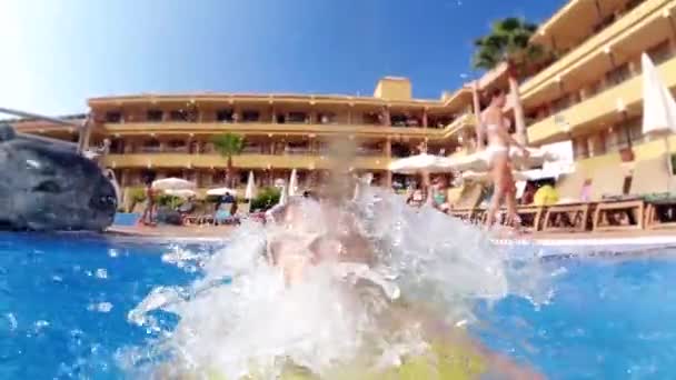 Відео повільного руху веселого маленького хлопчика з надувним кільцем, що бризкає воду і сміється в басейні — стокове відео