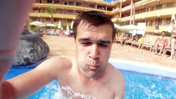 Видео медленного движения молодого человека, прыгающего в открытый бассейн на летнем курорте отеля — стоковое видео