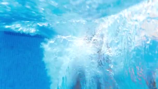 Slow motion video of funny young man holding thumb up while jumping in swimming pool and diving underwater — Stock Video