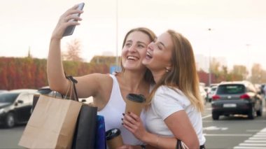 Alışveriş yaptıktan sonra akıllı telefon kamerasıyla selfie çekerken gülümseyen ve gülen iki kızın 4k videosu.