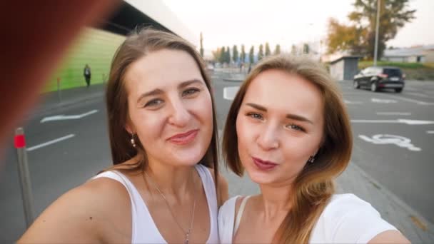 4k POV video de dos hermosas chicas sonrientes haciendo selfie en la cámara del teléfono inteligente en la calle de la ciudad — Vídeo de stock
