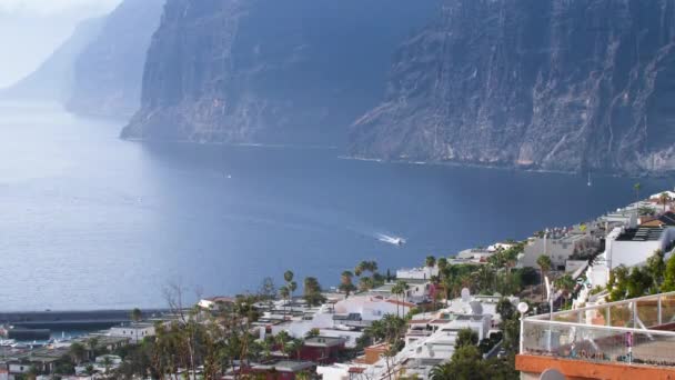 4k video of beautiful white motor boat riding in harbour surrounded by high big cliffs and mountains. Panoramic landscape of Los Gigantes, Tenerife, Canary islands — Wideo stockowe