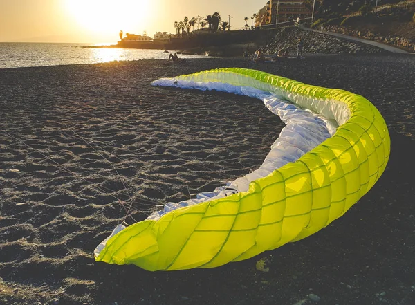 Tönendes Bild eines großen Fallschirms zum Gleitschirmfliegen, der bei Sonnenuntergang am Strand liegt — Stockfoto