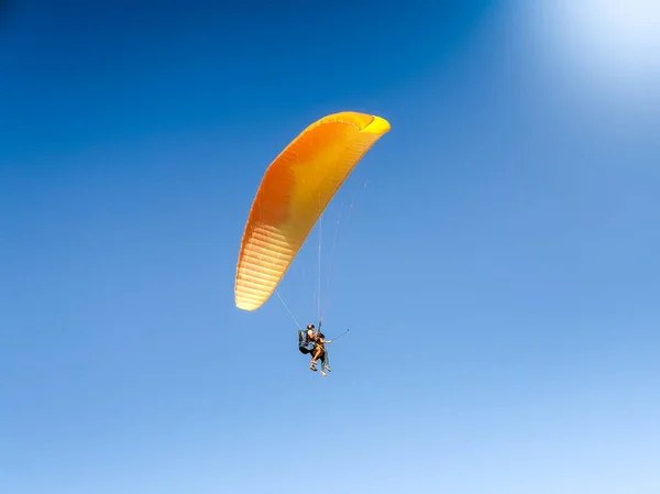 Bella immagine di istruttore professionista di parapendio con touris tflying sul paracadute contro cielo blu chiaro — Foto Stock