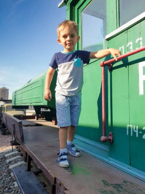 Buharlı lokomotifin üzerinde duran sevimli gülümseyen çocuğun portresi.