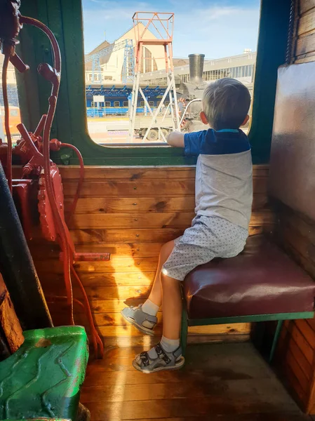 古い蒸気機関車の機関車や列車のエンジニア席に座って窓の外を見ている小さな男の子 — ストック写真