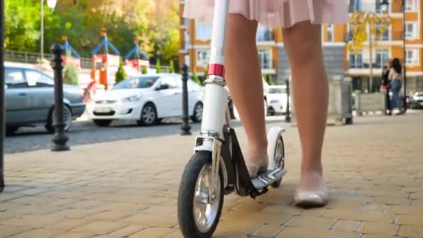 4k primer plano de vídeo de la cámara que se mueve desde los pies femeninos a la cara sonriente de la joven mujer que viaja al trabajo en scooter — Vídeo de stock