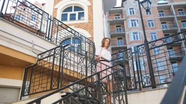 4k video de feliz sonriente joven mujer caminando por las escaleras y caminando en la calle de la ciudad en caliente día soleado — Vídeo de stock