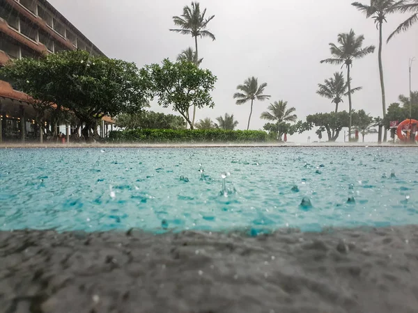 CLoseup photo of water droplets falling in swimming pool during tropical rain — Stock Photo, Image