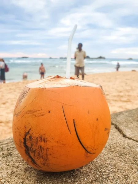 Closeup photo of tasty fresh yellow coconut lying on the sandy ocean beach — Stock Photo, Image