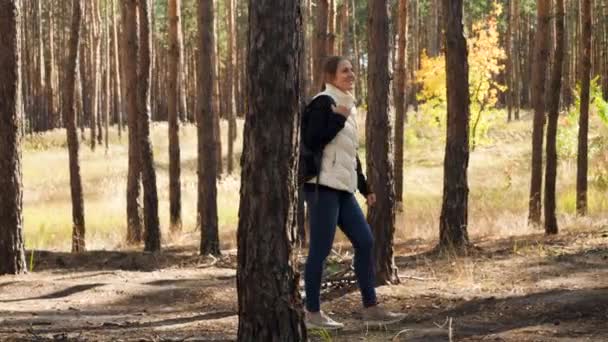 4k video of happy smiling young woman with backpack hiking in autumn forest on bright sunny day — Stok video