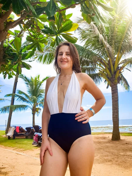 海のビーチで手のひらの下にポーズの水着で美しい笑顔の若い女性の肖像画 — ストック写真