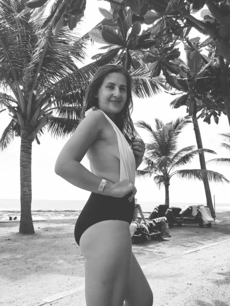 Retrato preto e branco de bela jovem mulher em pé na praia do mar sob palmeiras — Fotografia de Stock