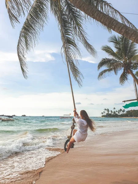 Foto tonificada de hermoso joven wman balanceándose en la palmera en la playa — Foto de Stock