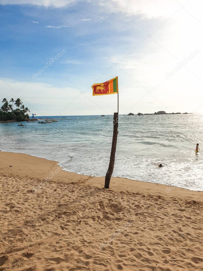 Beautiful image of flag of Sri Lanka fluttering under wind on the ocean beach at Hikkaduwa