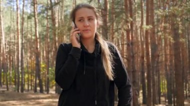 4k video of camera flying around beautiful young woman talking by phone in the forest