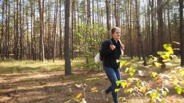 4k кадри щасливої усміхненої жінки, яка посміхається під час піших прогулянок у лісі в сонячний день — стокове відео