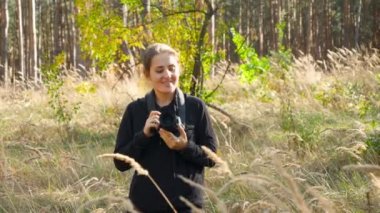4k video of young female wildlife photographer journalist walking with camera in forest and looking for animals