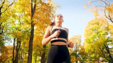 4k video from low point of view on young beautiful woman running at autumn park on bright sunny day