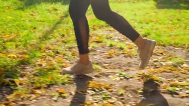 4k slow motion video of young sporty woman running in the autumn park against bright sun