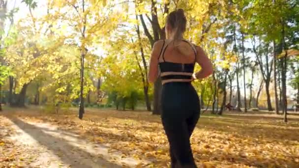 Vidéo au ralenti 4k de la jeune femme se sentant fatiguée et faisant une pause après avoir regardé sa montre intelligente de remise en forme tout en courant et en faisant des exercices au parc — Video