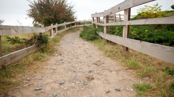 4k video di camminare su un lungo sentiero in campagna accanto a una lunga recinzione in legno in fattoria o rancho — Video Stock