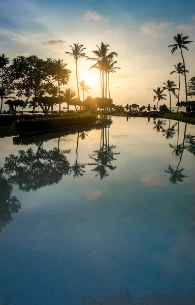 Prachtig beeld van zonsopgang door kokospalmen boven het zwembad in hotel resort — Stockfoto