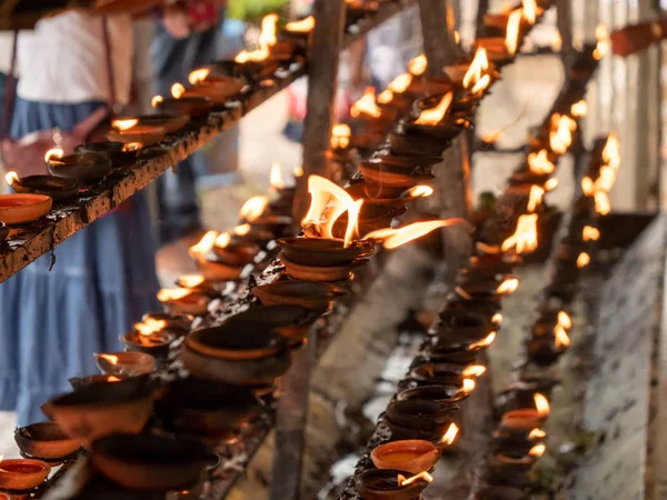 Closeup photo of oil lamps and lanterns burning in the place of worship at buddhist temple — ストック写真
