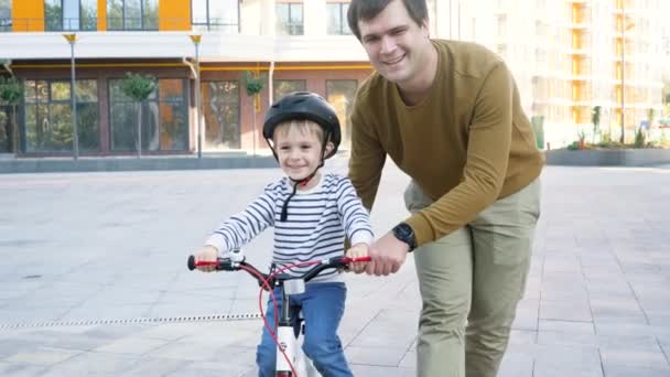 4k filmagem do jovem pai ensinando seu filho a andar de bicicleta na rua — Vídeo de Stock