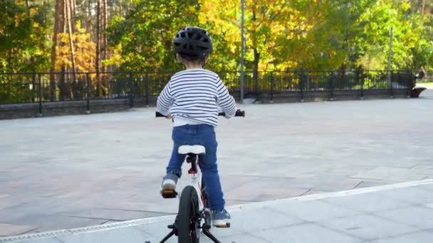 4k video of happy cheerful little boy learning and riding bicycle on city street — Stockvideo