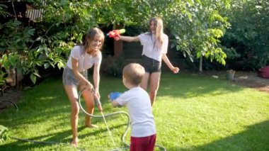 4k slow motion footage of happy family with little boy having water gun fight at backyard