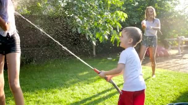 4k vídeo de adolescentes felizes e crianças brincando com armas de água e mangueira de jardim e tendo batalha de água no quintal — Vídeo de Stock