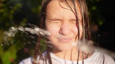 Closeup slow motion video of teenage girl closing eyes while water stream splashing in her face