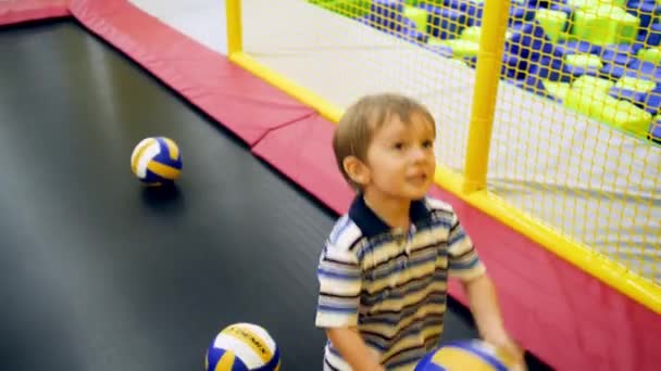 Vidéo 4k de petit garçon lançant des balles dans l'anneau de basket sur le trampoline à l'aire de jeux pour enfants dans le centre commercial — Video