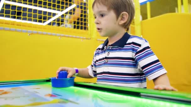 4k vídeo of happy little boy playing in air hockey at amusement park — Vídeo de Stock