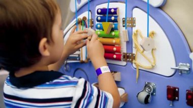 Closeup 4k video of little toddler boy playing with wooden educational board in kindergarten