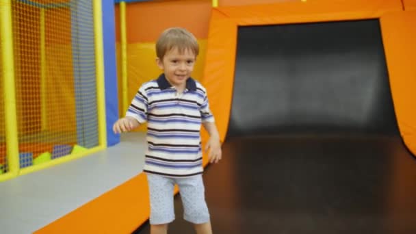 4k vídeo of happy laughing 4 years old boy playing and jumping on trampolins on the playground — Vídeo de Stock