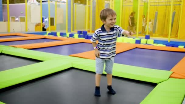 4k video de niño feliz divirtiéndose y pasándolo bien mientras salta y salta en trampolines en el centro comercial — Vídeo de stock