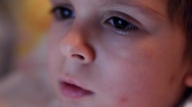 Closeup 4k video of little toddler boy rubbing his eyes feeling tired at night. Tablet computer screen reflecting in childs eyes