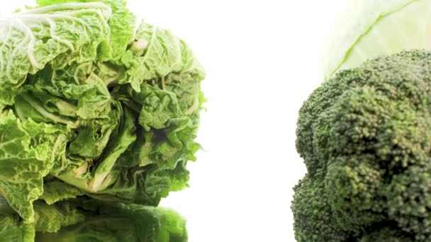 4k dolly video of fresh lettuce leaves and broccoli lying on white background. Concept of healthy nutrition and organic food. Perfect shot for vegetarian or vegan — Wideo stockowe