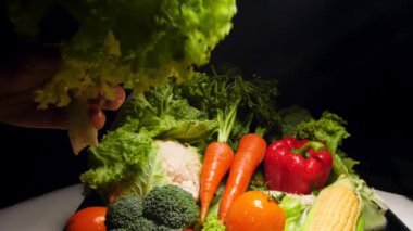 Closeup slow motion video of female hand shaking wet lettuce leaves and splashing water droplets over kitchen table. Concept of healthy nutrition and organic food. Perfect background for vegetarian or