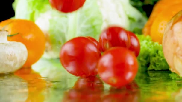 Closeup vídeo em câmera lenta de tomates vermelhos caindo na mesa molhada contra legumes frescos. Conceito de nutrição saudável e alimentos orgânicos. Fundo perfeito para vegetariano ou vegan. Cozinhar e culinária — Vídeo de Stock