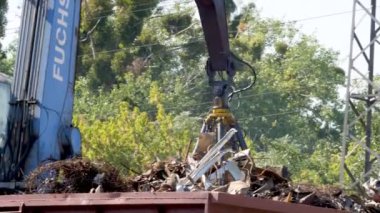 4k footage of claw manipulator picking up, moving and throwing metal scrap. Concept of metal recycling on scrapyard