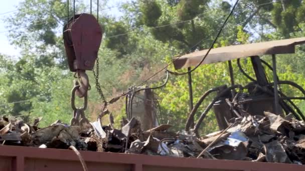 Filmagem 4k de grande ímã industrial no ferro de elevação do ferro-velho e carregando-o em recipiente de metal. Conceito de reciclagem de metais — Vídeo de Stock