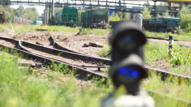 4k filmato di telecamera che si concentra da lunghi treni merci su ferrovia a semaforo con luce blu. Concetto di trasporto e carico per ferrovia — Video Stock