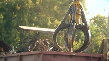 4k footage of working hydraulic claw manipulator used for sorting and moving heavy metal junk on scrapyard. Concept of metal recycling on junkyard